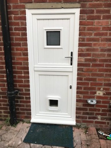 upvc door range White door with a small window and a pet flap, set against a red brick wall.